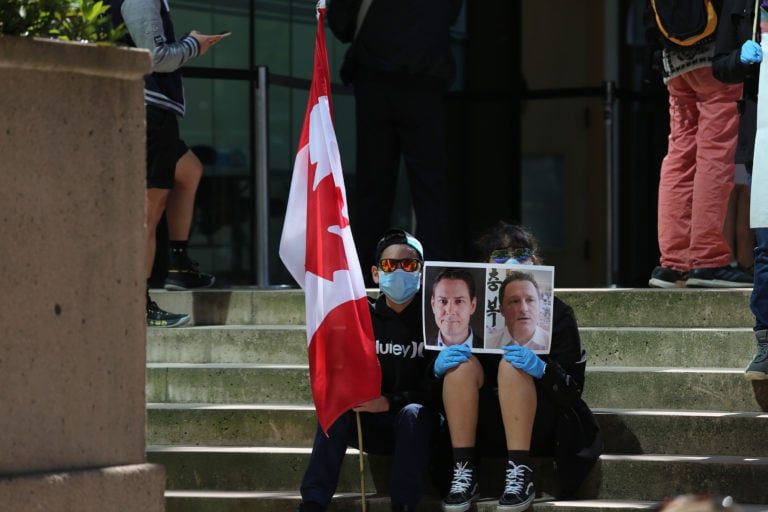 Protestors hold a banner and a Canadian flag as they gather outside the BC Supreme Court for Meng Wanzhou's hearing in Vancouver in May (Mert Alper Dervis/Anadolu Agency via /Getty Images)