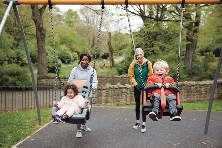 Two mothers are pushing their kids on the swings in the park. (SolStock/Getty Images)
