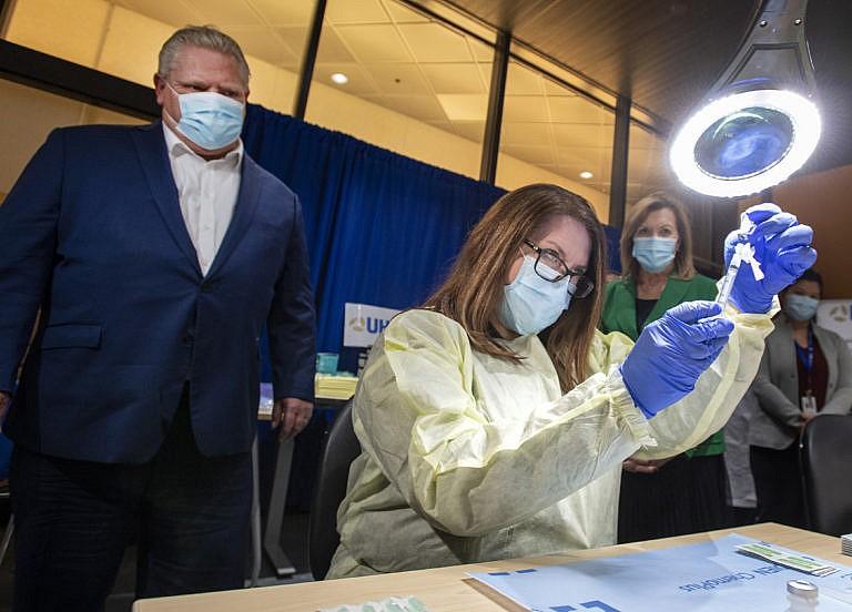 Ontario Premier Doug Ford looks on as a dose of the Pfizer-BioNTech COVID-19 vaccine is prepared by Pharmacy Technician Supervisor Tamara Booth Rumsey at The Michener Institute in Toronto on Monday, January 4, 2021. THE CANADIAN PRESS/Frank Gunn
