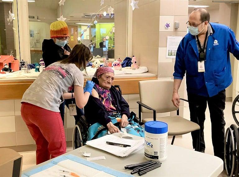 Eunice Fiddler, 85, receives a COVID-19 vaccine from Andrea McWatters as her daughter Margaret Beardy and interpreter Tom Chapman look on in Sioux Lookout, Ont. Thursday, Jan.7, 2021. THE CANADIAN PRESS/HO-Sioux Lookout Meno Ya Win Health Centre MANDATORY CREDIT