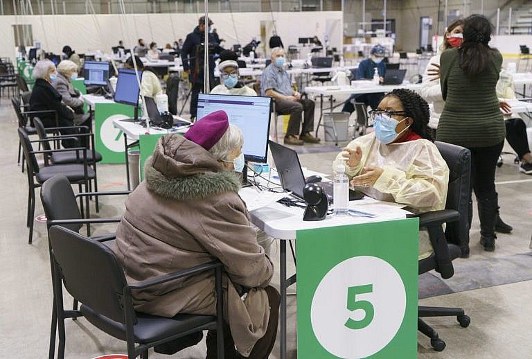 Seniors register at a COVID-19 vaccination clinic in a hockey arena in Montreal. (Paul Chiasson/CP)