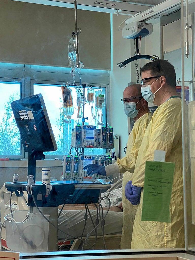 Dr. Darren Markland (background) performs a point of care cardiac ultrasound on an ICU patient at the Royal Alexander hospital during the height of the second wave of the covid pandemic, while Dr. Curtis Johnston consults. (Courtesy of Dr. Markland)