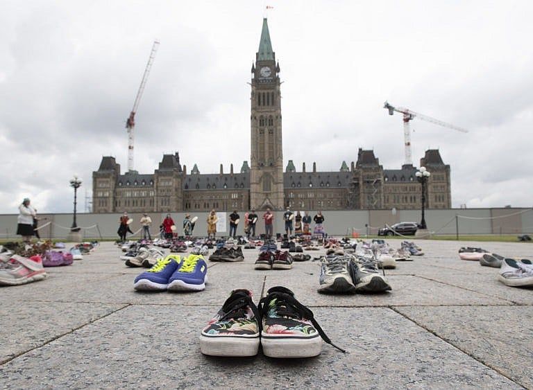 Shoes sit in front of the Parliament buildings during a ceremony on June 3, 2021 in Ottawa (Adrian Wyld/CP)
