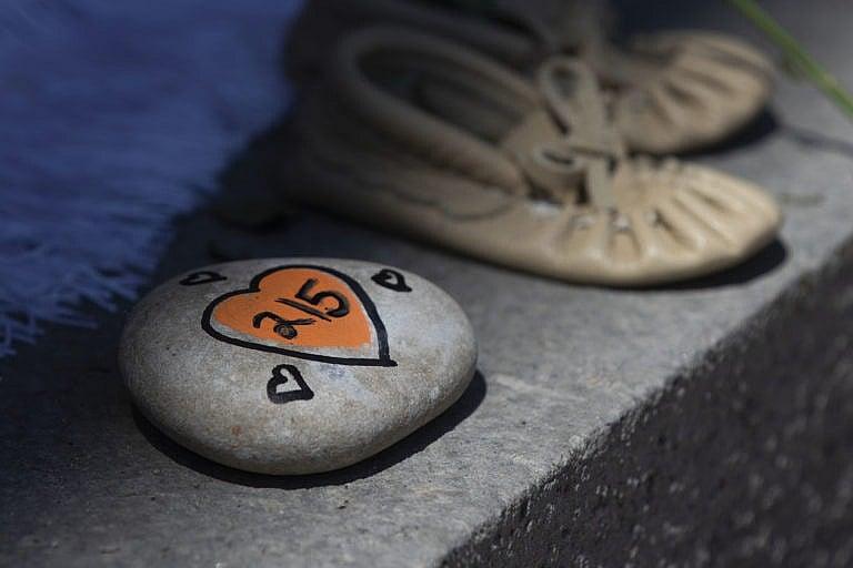 A rock with 215 painted on it is shown before a ceremony in Kingston, Ont., on Monday, May 31, 2021. The remains of 215 children were recently discovered on the grounds of the former Kamloops Indian Residential School. THE CANADIAN PRESS/Lars Hagberg