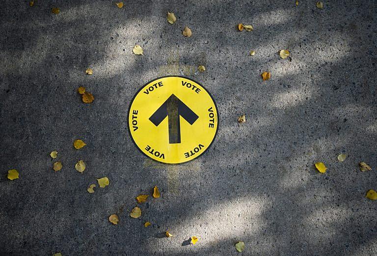 A sign directing voters to a polling station is taped to the sidewalk among autumn leaves, on election day of the 2019 federal election, in Ottawa, Monday, Oct. 21, 2019. (Justin Tang/Canadian Press)