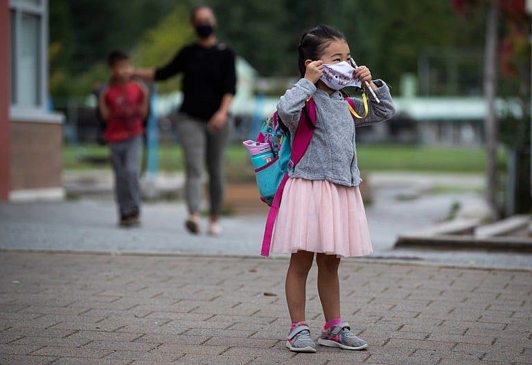 Avalynn Kwok, 4, puts on her face mask to curb the spread of COVID-19 as her parents drop her off at Lynn Valley Elementary School for her first day of kindergarten, in North Vancouver, B.C. (Darryl Dyck/CP)