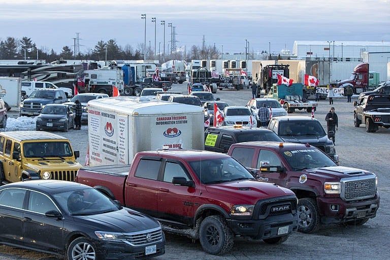 Vehicles with Canadian flags, part of the “Freedom” convoy, line up before the departure from Kingston to Ottawa, Friday, Jan. 28, 2022. (Lars Hagberg/The Canadian Press)
