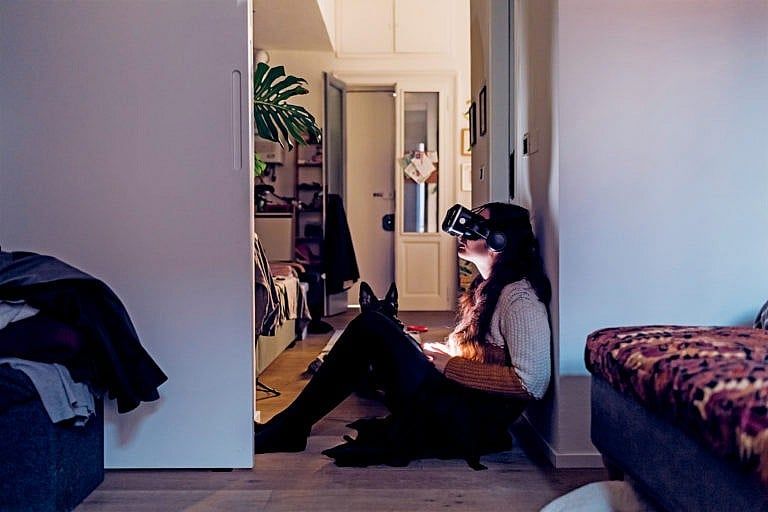 Woman with virtual reality headset sitting by wall at home (Westend61/Eugenio Marongiu/Getty Images)