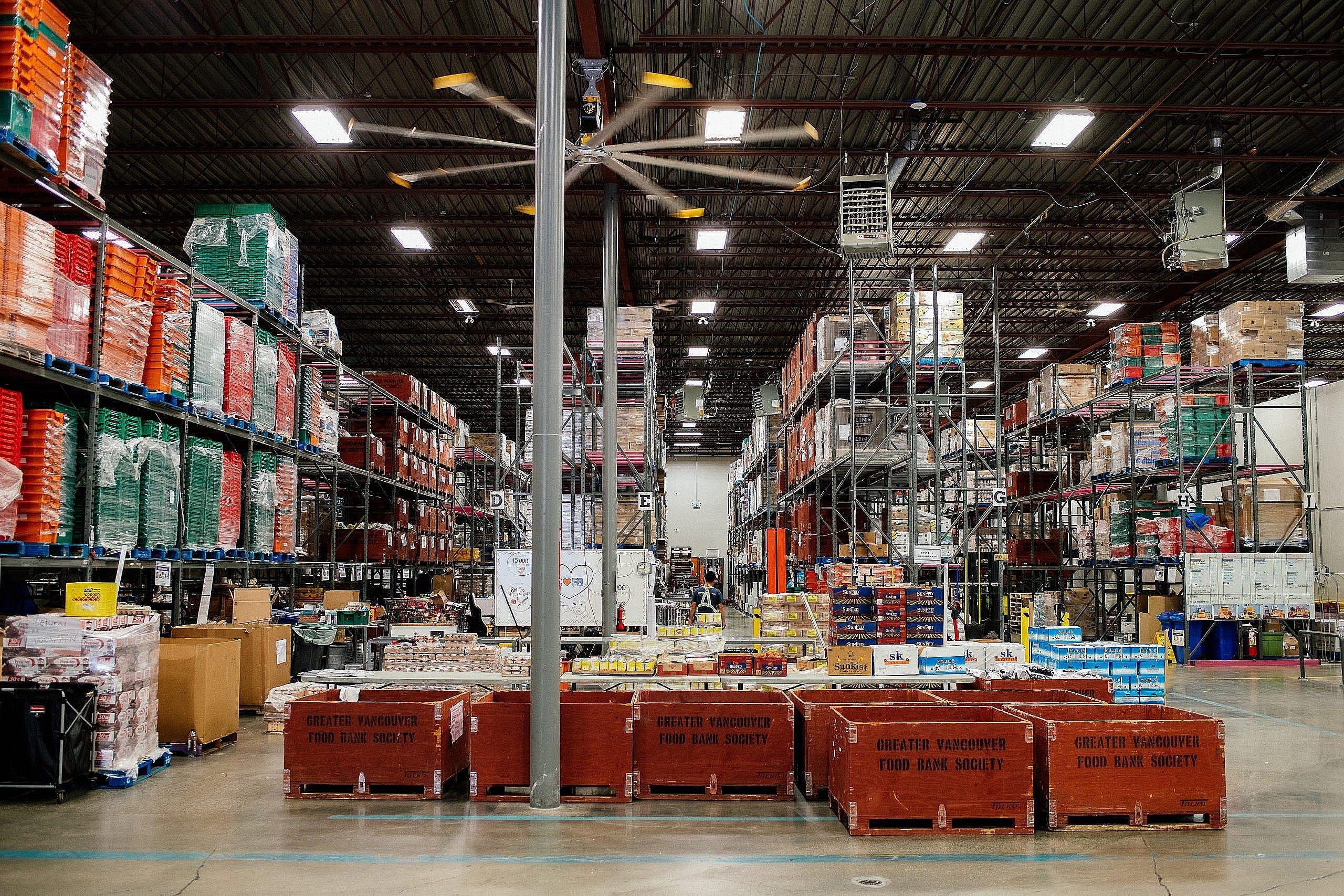 wide angle shot of various containers and shelves in a warehouse stocked with food for a food bank
