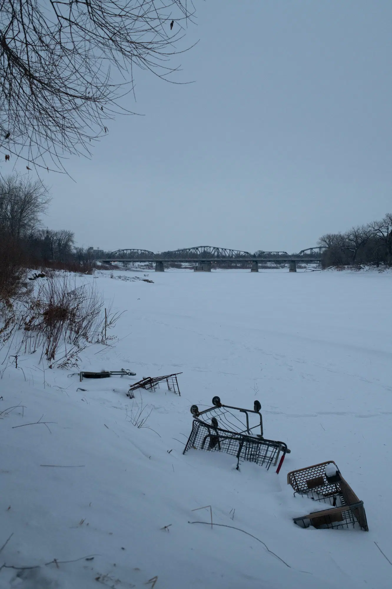 A picture of a frozen river with a bridge in the distance.